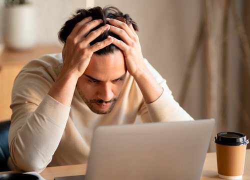 Мужчина испытывает усталость Мужчина сидит склонив голову в руки